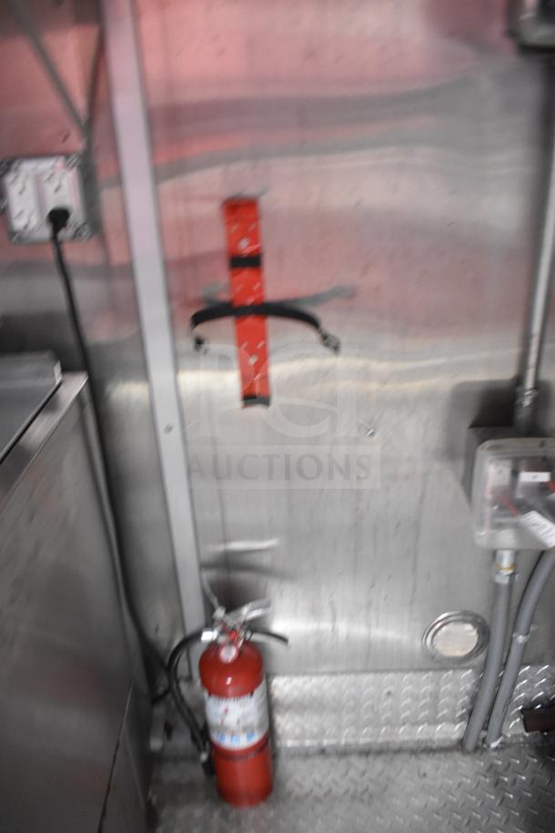 2021 Rock Solid Cargo 28ft food trailer interior with stainless steel walls, electrical outlets, and a mounted fire extinguisher.