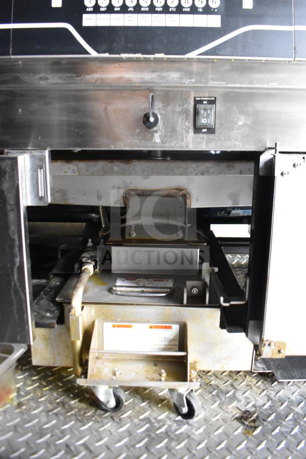 2021 Rock Solid Cargo 28ft food trailer interior showing kitchen equipment. Features visible include a Henny Penny Electric Fryer on a diamond-plate floor with power switch and casters for mobility.