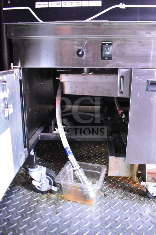 Interior of 2021 Rock Solid Cargo 28ft food trailer, showing equipment storage with visible fryer parts and drainage system.