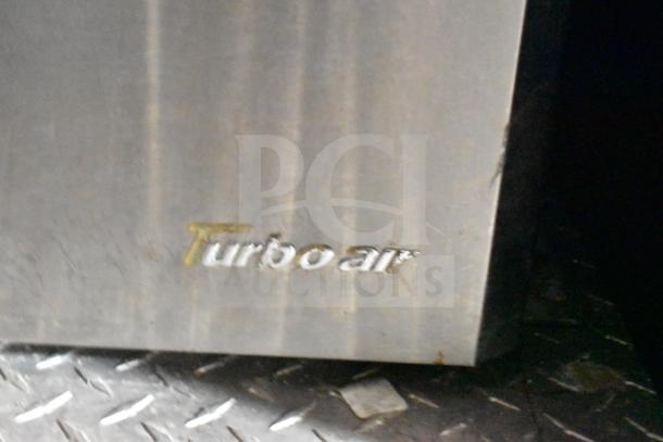 "Turbo Air" logo on the side of a metal commercial food trailer. Surface shows wear and minor scratches.