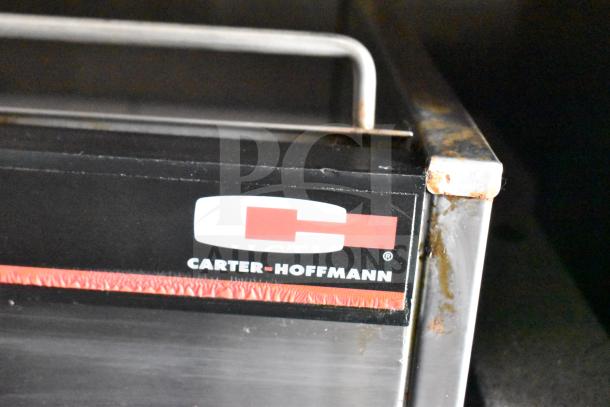 Close-up of a Carter-Hoffmann stainless steel appliance corner, showing logo and visible rust, part of a 2021 Rock Solid Cargo trailer.