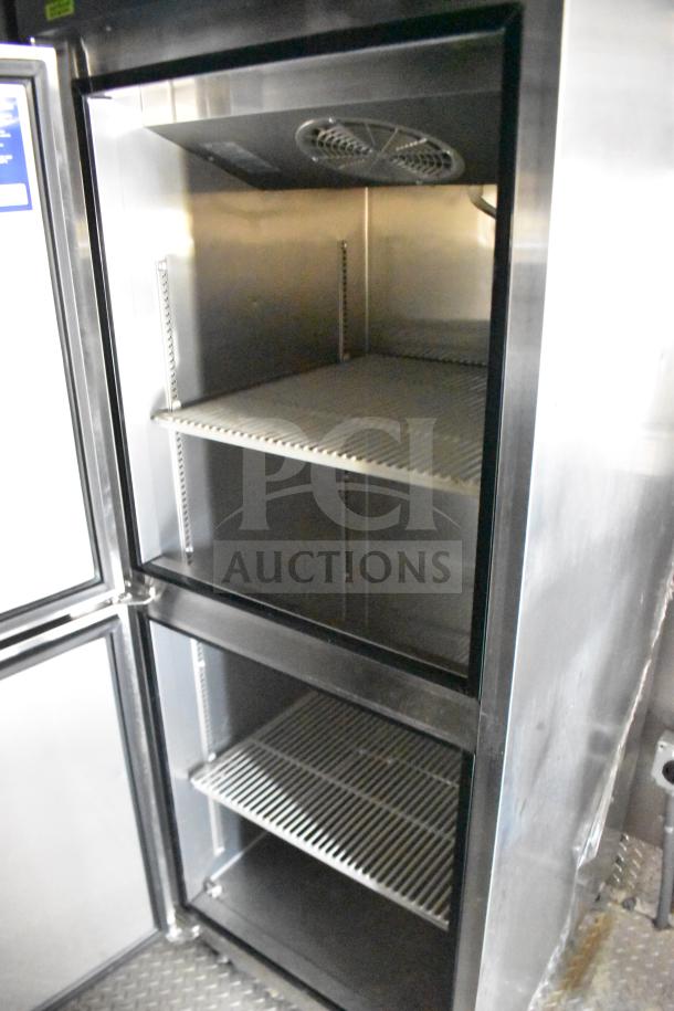 Stainless steel commercial refrigerator interior in Rock Solid Cargo 28ft food trailer, featuring shelving and cooling vents.