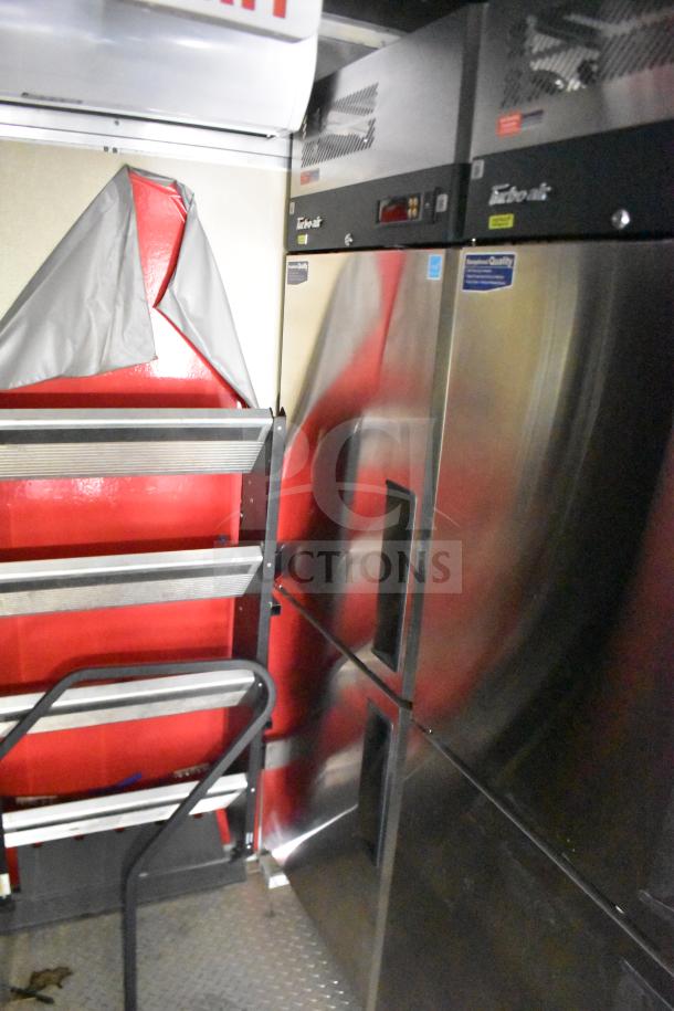 Interior view of a 2021 Rock Solid Cargo 28ft food trailer featuring refrigeration units and storage, showcasing stainless steel surfaces.