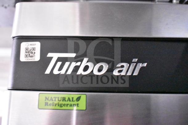 "Turbo Air" branding on stainless steel refrigerator, marked with "Natural Refrigerant" label and QR code sticker.
