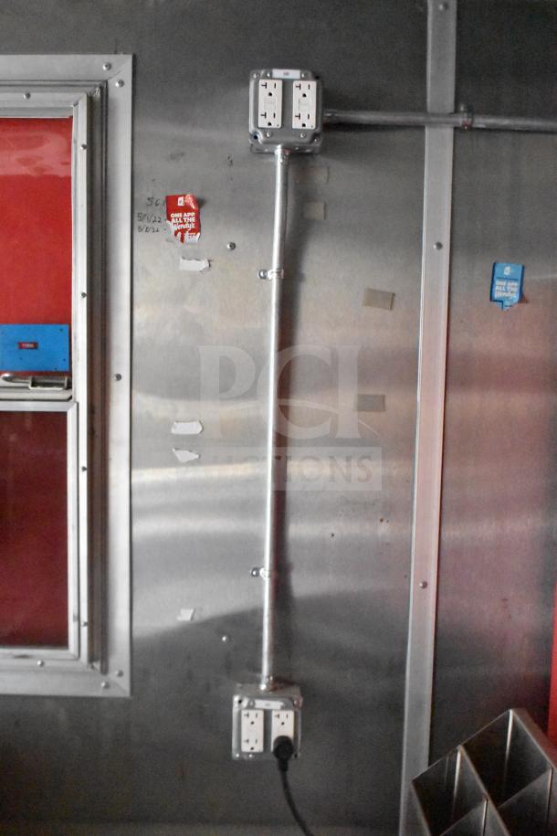 Interior view of 2021 Rock Solid Cargo 28ft food trailer, showing electrical outlets and stainless steel wall finish.
