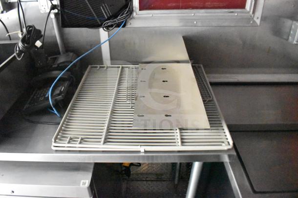 Interior view of a 2021 Rock Solid Cargo 28ft food trailer; includes wiring and shelving on stainless steel counters.