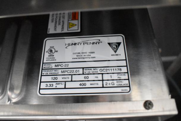 Close-up of Henny Penny fryer label, model MPC-22, showing specifications: 120 volts, 60 Hz, 400 watts, serial GC2111178.