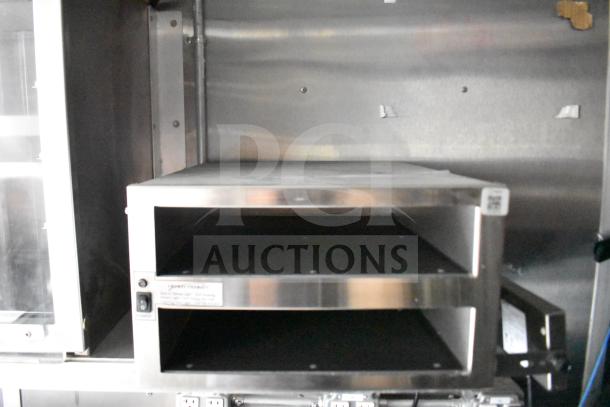 Interior view of a 2021 Rock Solid Cargo food trailer showcasing a stainless steel commercial appliance shelf, in excellent condition.