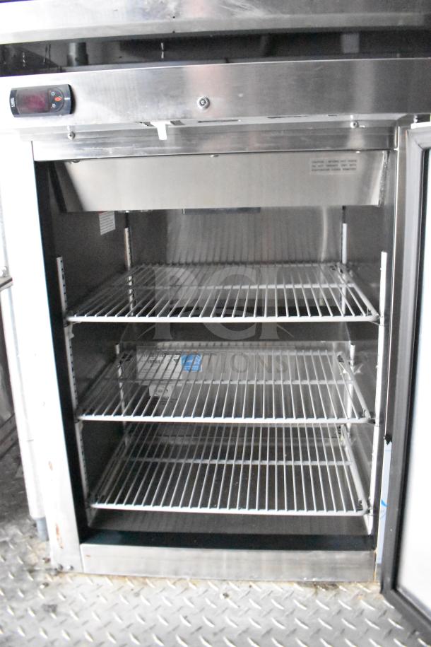 Interior of 2021 Rock Solid Cargo food trailer refrigerator, showcasing three wire shelves, stainless steel construction, and digital controls.