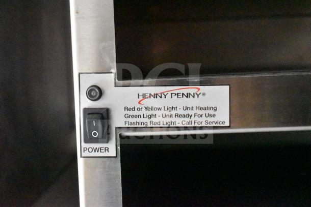 Henny Penny fryer control panel with power switch and status light indicator for heating and service alerts.