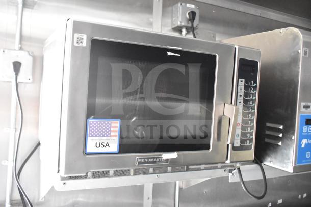 Menumaster commercial microwave with keypad and "Fabricated and Assembled in the USA" sticker, mounted in trailer kitchen.