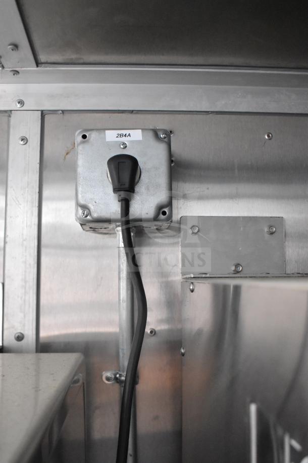 Electrical outlet inside 2021 Rock Solid Cargo 28ft food trailer, labeled "2B4A", with attached power cord.