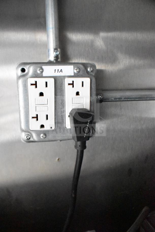 Electrical outlet inside 2021 Rock Solid Cargo food trailer, featuring two dual sockets labeled "11A" with a plugged-in cord.