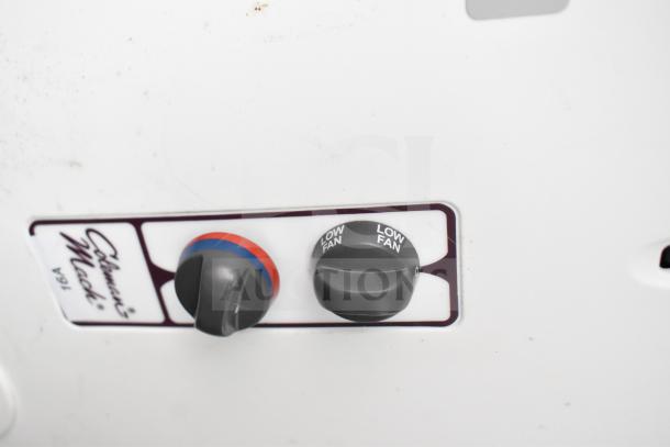 Close-up of control panel featuring two black dials labeled "Coleman Mach" and "Low Fan" on a white background.