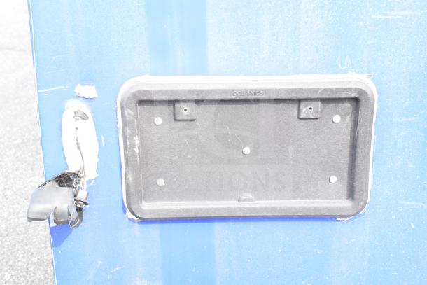 Blue food trailer with a license plate holder and door latch. Features dual Pitco gas fryers, CaptiveAire hood, Arctic Air refrigeration, and Daikin mini-split.