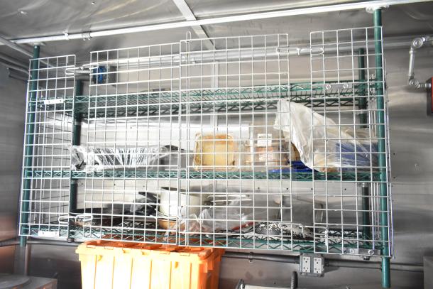 Interior view of NBRHD Kitchens Ghost Kitchen food trailer with wire shelving, storage containers, and kitchen utensils.