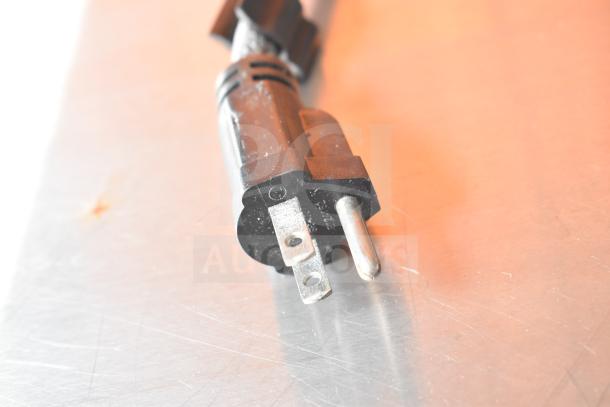 Power plug on stainless steel surface; part of the NBRHD Kitchens Ghost Kitchen Food Trailer equipment.