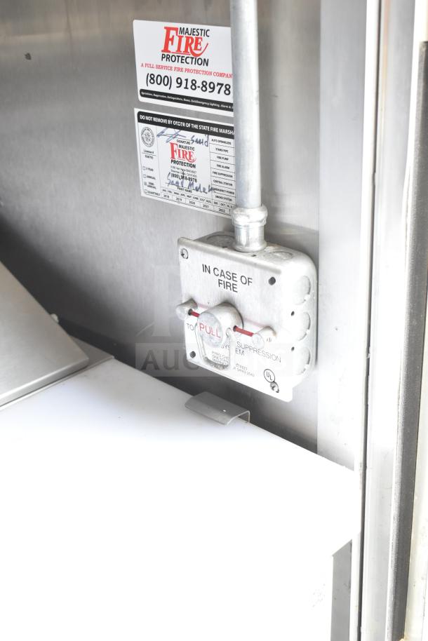 Fire safety system inside NBRHD Kitchens Ghost Kitchen trailer, featuring Majestic Fire Protection labels and a fire pull station.