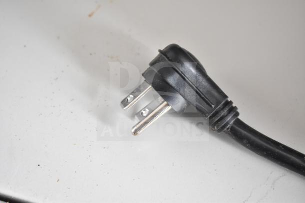 Close-up of a standard black electrical plug, likely part of the NBRHD Kitchens Ghost Kitchen Food Trailer's equipment.