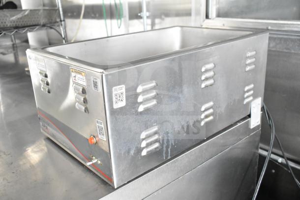 Stainless steel food warmer with vented sides, warning labels, and QR code.