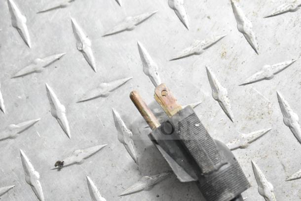 "Close-up of a power plug on diamond plate metal flooring, related to NBRHD Kitchens Ghost Kitchen Food Trailer equipment."