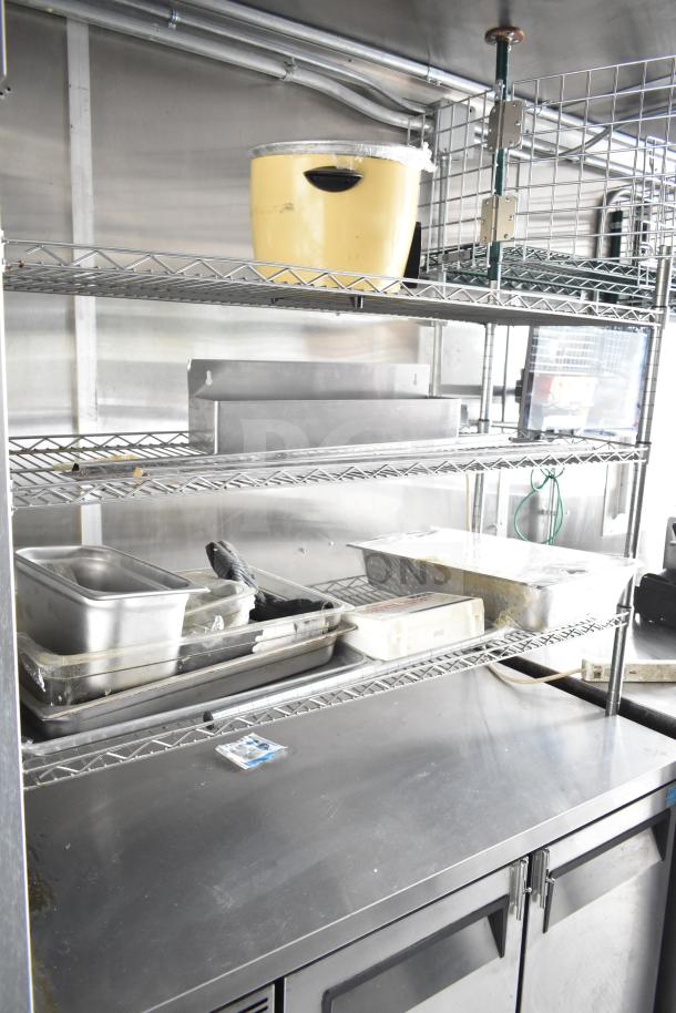 NBRHD Kitchens Ghost Kitchen trailer interior with shelving, a rice cooker, and kitchen utensils. Commercial setup shown.