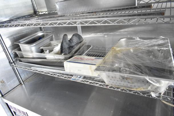 Interior shelves of NBRHD Kitchens food trailer with containers and packaging, featuring stainless steel surfaces.
