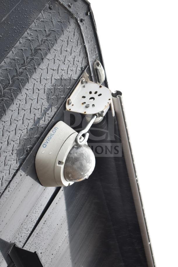 2020 Southern Dimensions Group mobile trailer with Avigilon security camera mounted. All-black exterior, water droplets visible.