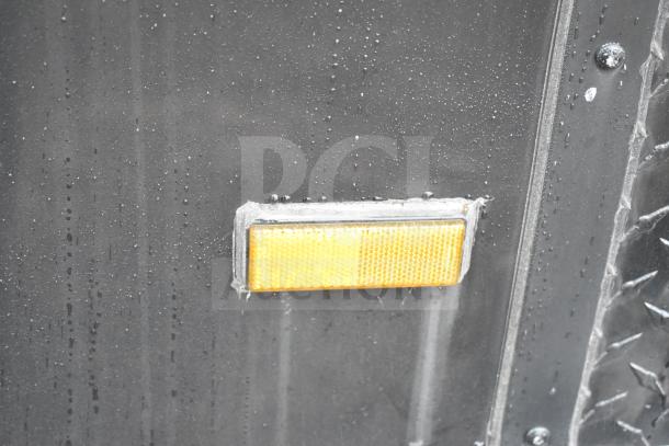 Reflector on black commissary trailer exterior with visible water droplets.