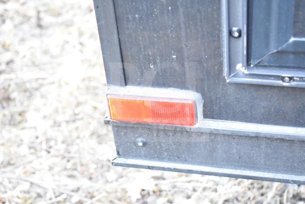 Close-up of an all-black mobile commissary trailer corner with an orange reflector.