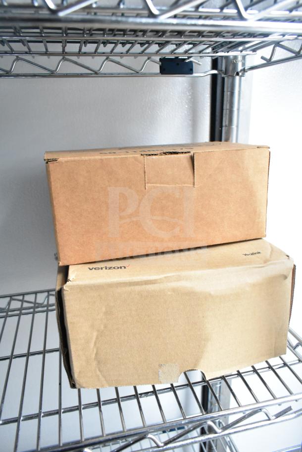 Silver wire shelving with two cardboard boxes; one box labeled "Verizon" visible, with no additional details apparent.