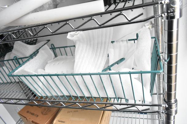 Metal wire shelving unit with plastic packaging materials and cardboard boxes.