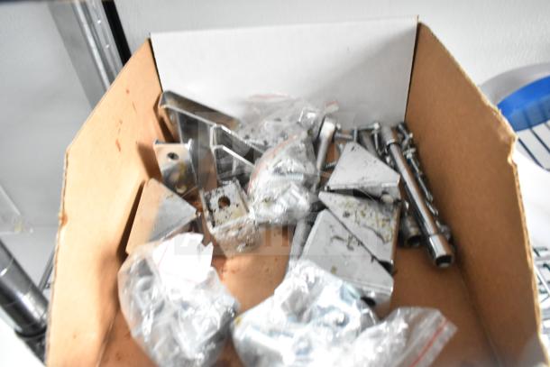 A box of assorted metal brackets, screws, and hardware components, in used condition.