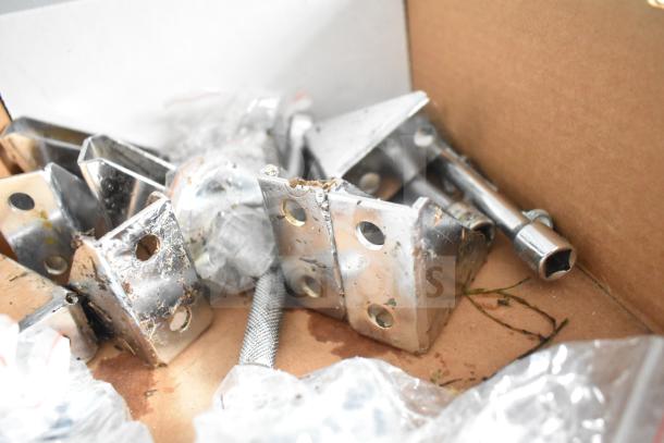 Box of metal brackets and hardware items, possibly related to trailer assembly, showing signs of wear and corrosion.