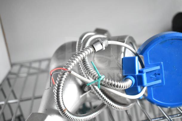 Coiled metal conduit with colored wires and a blue connector, resting on wire shelving.
