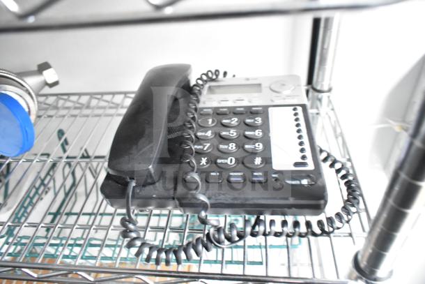 Black corded telephone on metal wire shelving inside mobile commissary trailer.