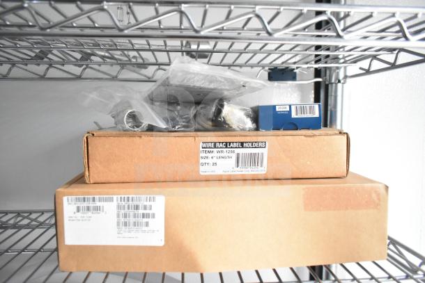 Boxes and bags of items, including wire rac label holders, are neatly arranged on metal shelves in a trailer.