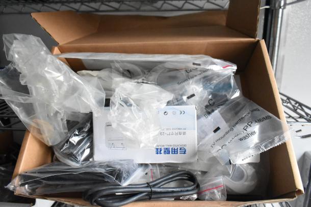 Box containing various packaged hardware components, cables, and installation accessories, labeled in English and another language.