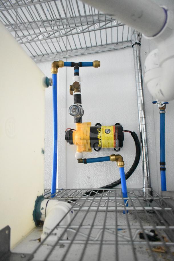 Interior view of Southern Dimensions Group mobile trailer showing plumbing components and wire shelving.