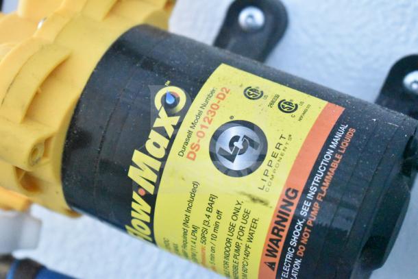 Close-up of a Flow Max water pump by Lippert Components. Model number DS-01230-D2 is visible on a yellow label.