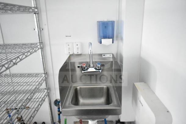 Stainless steel sink with dual handles and adjacent wire shelving inside 2020 Southern Dimensions Group trailer.