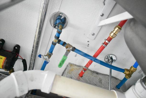 Plumbing system inside a 2020 Southern Dimensions Group trailer, showing blue and red pipes with valves and fittings.