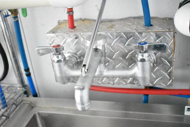 Close-up of dual faucet setup in 2020 Southern Dimensions Group commissary trailer, featuring metal handles and connected plumbing.