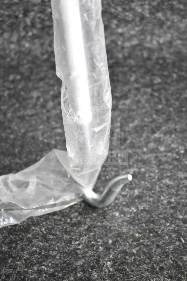 A close-up of a metal hook wrapped in plastic on a textured dark surface.