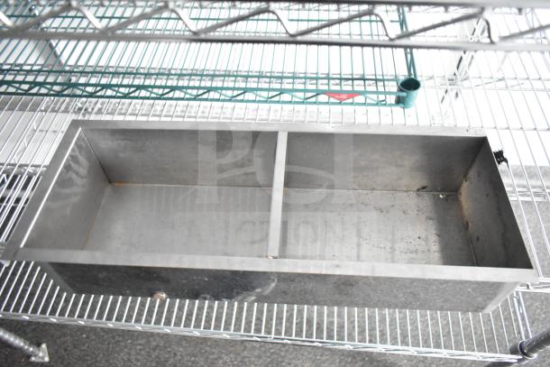 Metal wire shelving unit with dual-compartment steel box on lower shelf, part of Southern Dimensions mobile trailer.