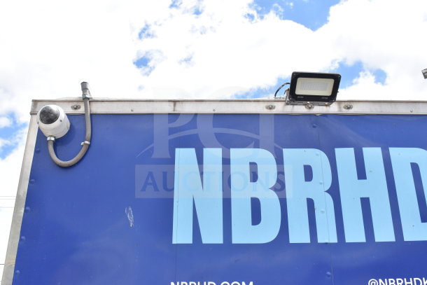 Blue exterior of a 2021 Rock Solid Cargo 28ft food trailer with security camera and lighting fixtures visible.