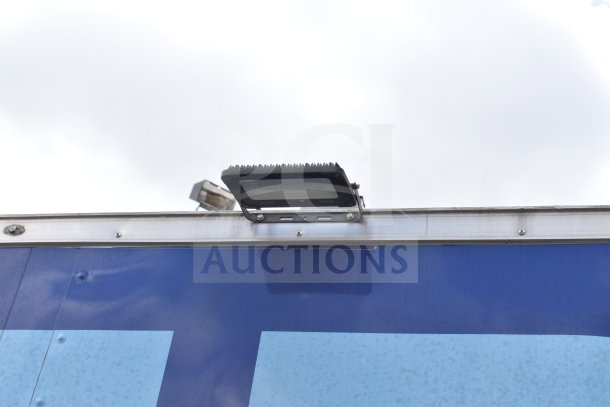 Exterior detail of 2021 Rock Solid Cargo 28ft food trailer, featuring LED flood light, blue paneling.