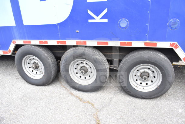 Triple axle of 2021 Rock Solid Cargo 28ft commercial food trailer, blue exterior with red and white trim, in new condition.