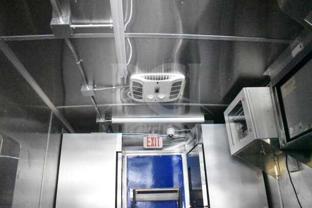 New 2021 Rock Solid Cargo 28ft food trailer interior with CaptiveAire hood, stainless steel walls, refrigeration unit, and exit sign.