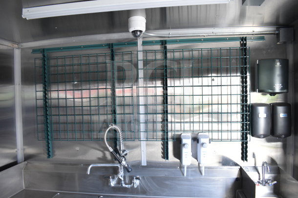 Interior of 2021 Rock Solid Cargo 28ft food trailer, showing stainless steel sink, faucet, wall racks, and soap dispensers.